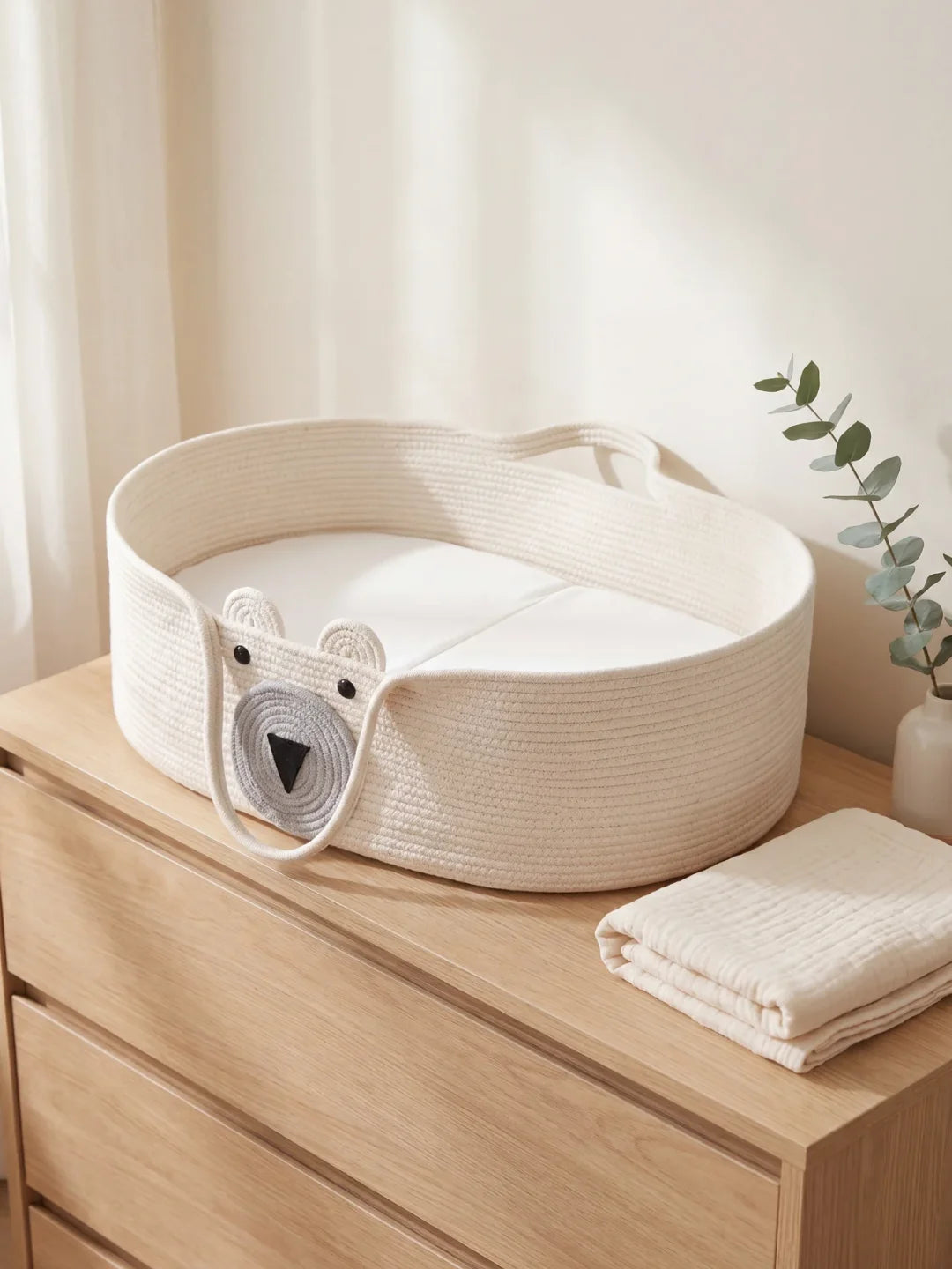 Panier à langer ourson écru en corde de coton posé sur une commode, décor chambre bébé