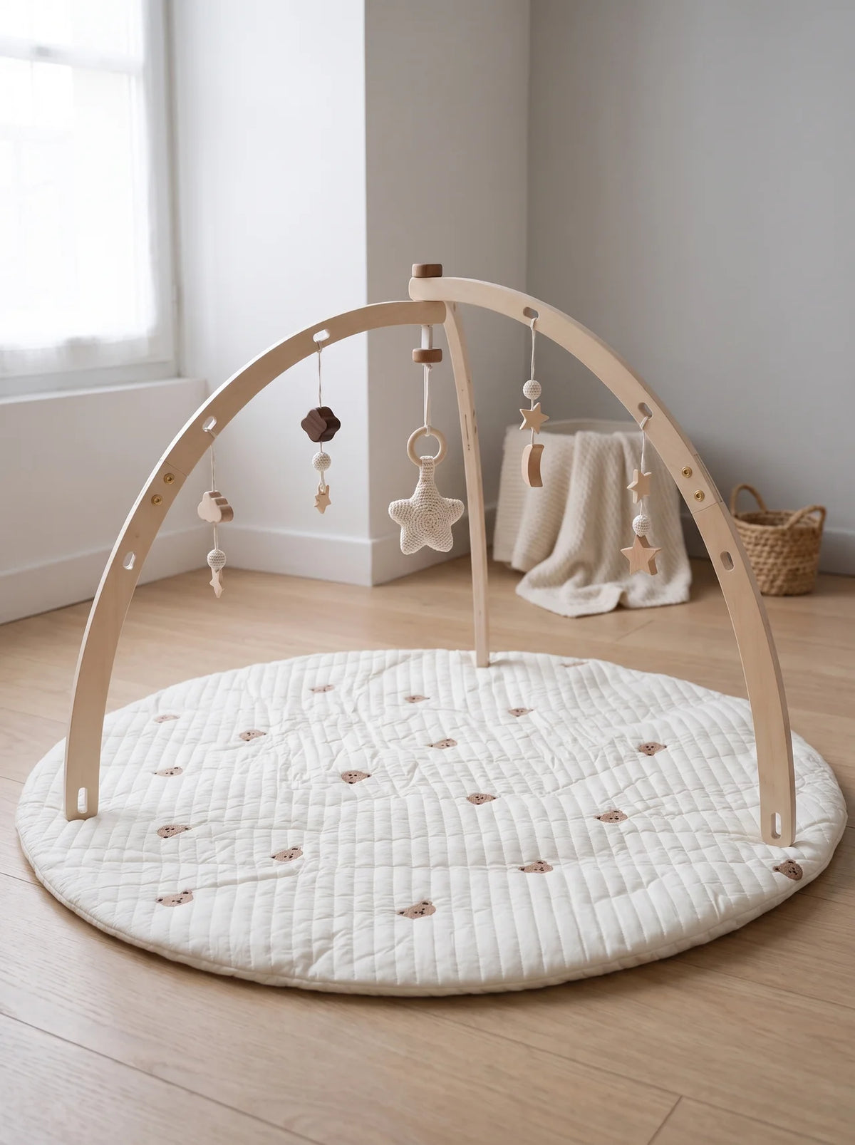 Arche d'éveil en bois en dôme posée sur un tapis d'éveil rond écru dans une chambre bébé lumineuse