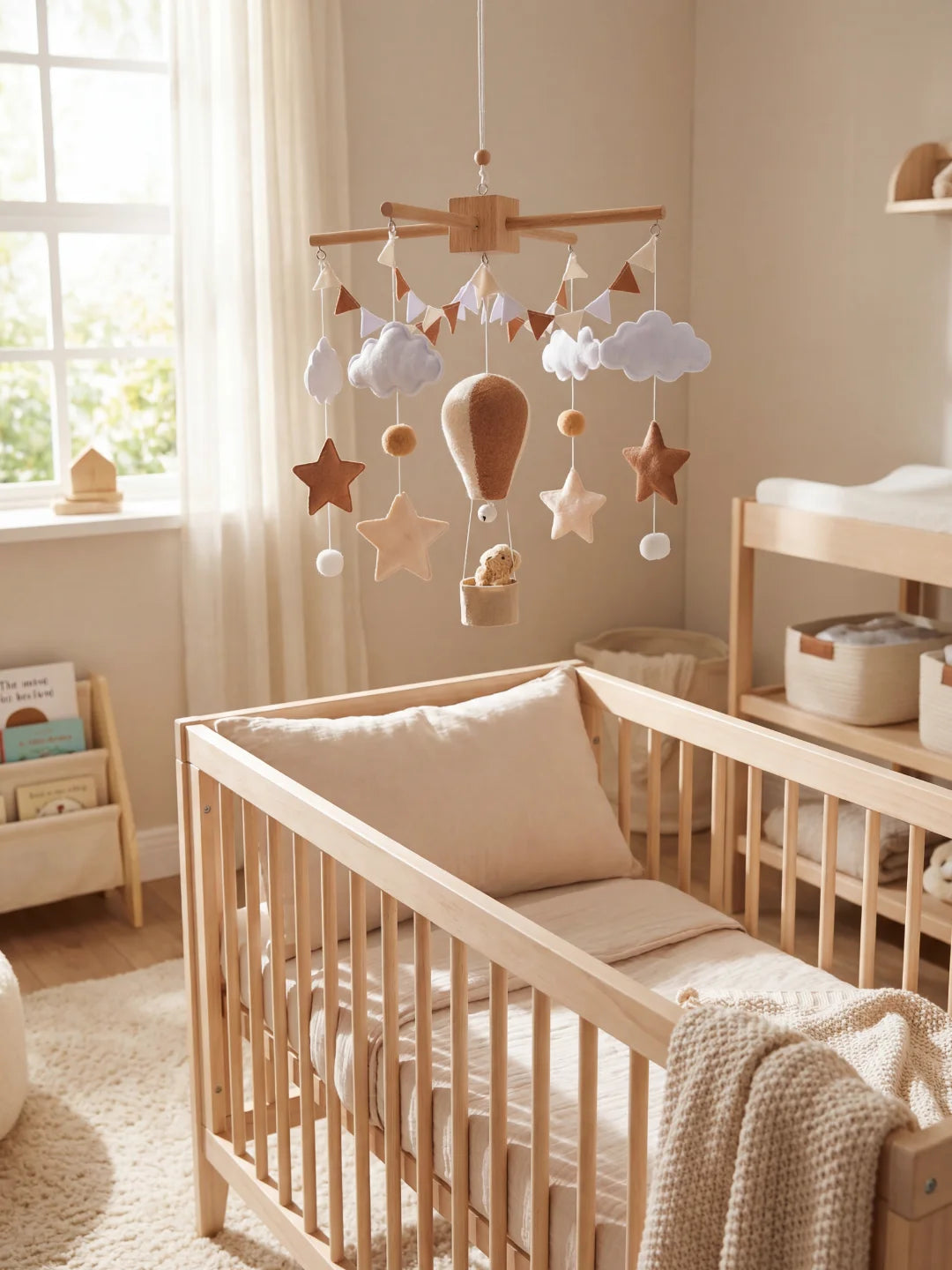 Chambre de bébé aux tons neutres avec mobile montgolfière marron et berceau bois.