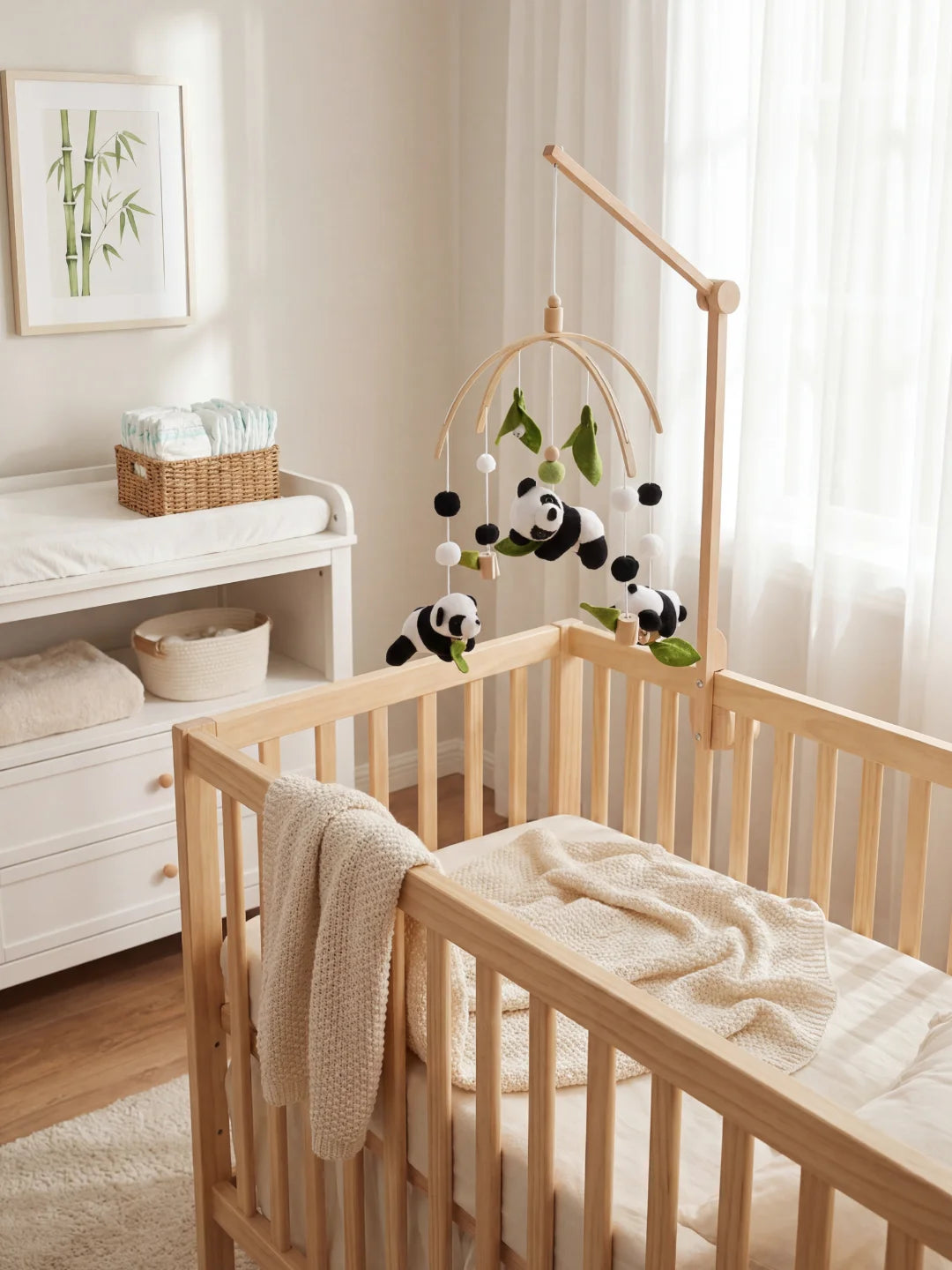 Aménagement d'un coin nuit bébé avec mobile panda, table à langer et cadre illustré bambou.