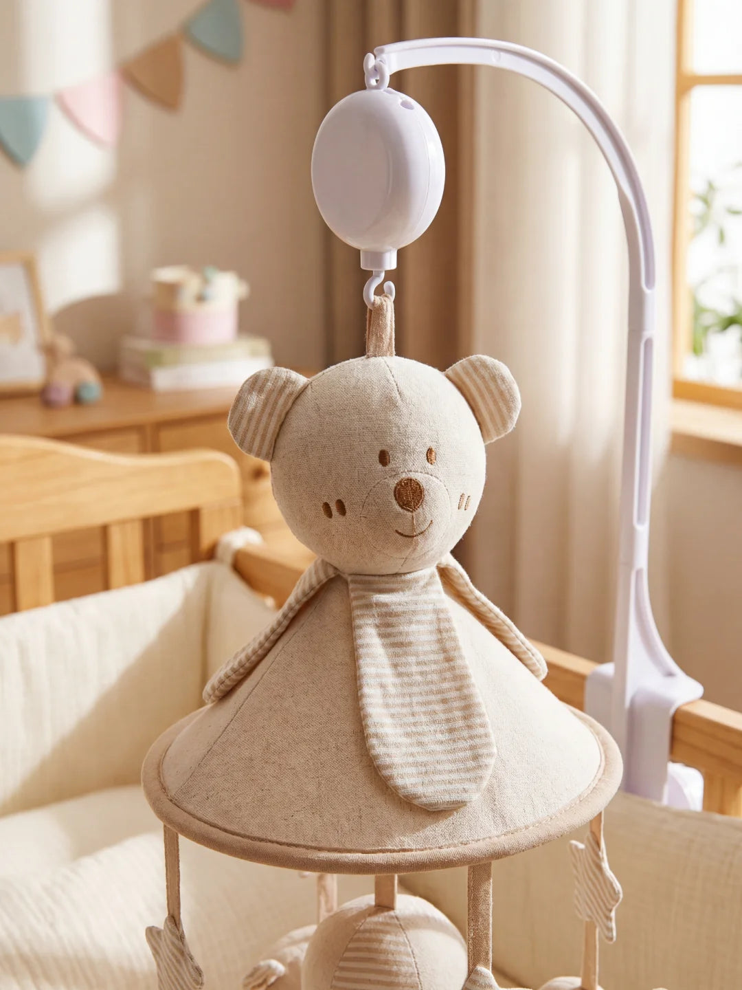 Gros plan sur la tête de l'ours en peluche central d'un mobile musical pour nouveau-né.
