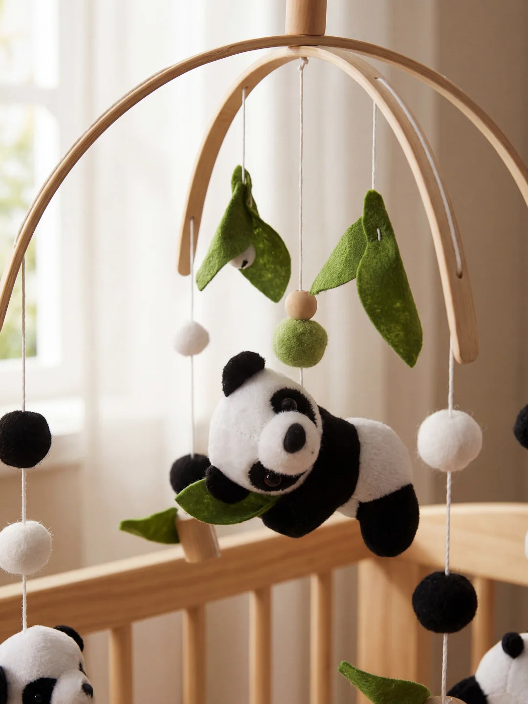 Zoom sur un petit panda en peluche noir et blanc tenant une feuille de bambou en feutrine verte.