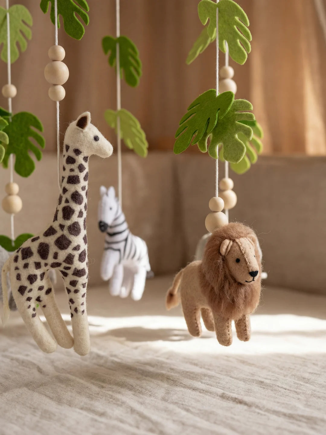 Détail des coutures et des matières d'un mobile bébé lion et girafe fait main.