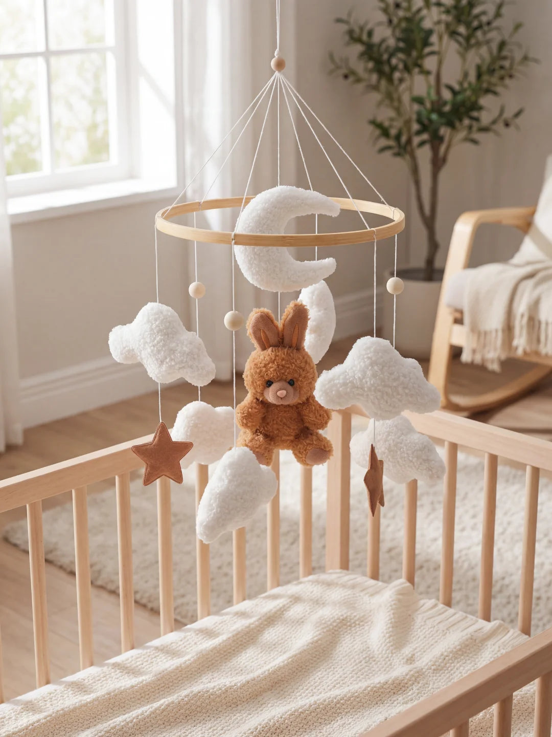 Mobile de lit pour bébé installé dans une chambre lumineuse avec fauteuil à bascule et plante.