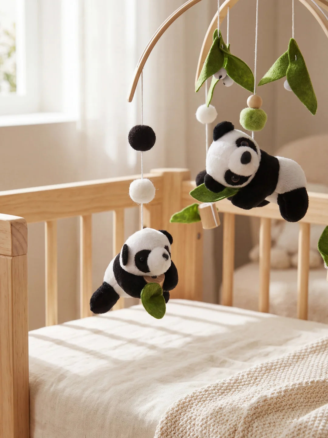 Détail des éléments d'éveil d'un mobile panda avec pompons contrastés pour stimuler la vue de bébé.