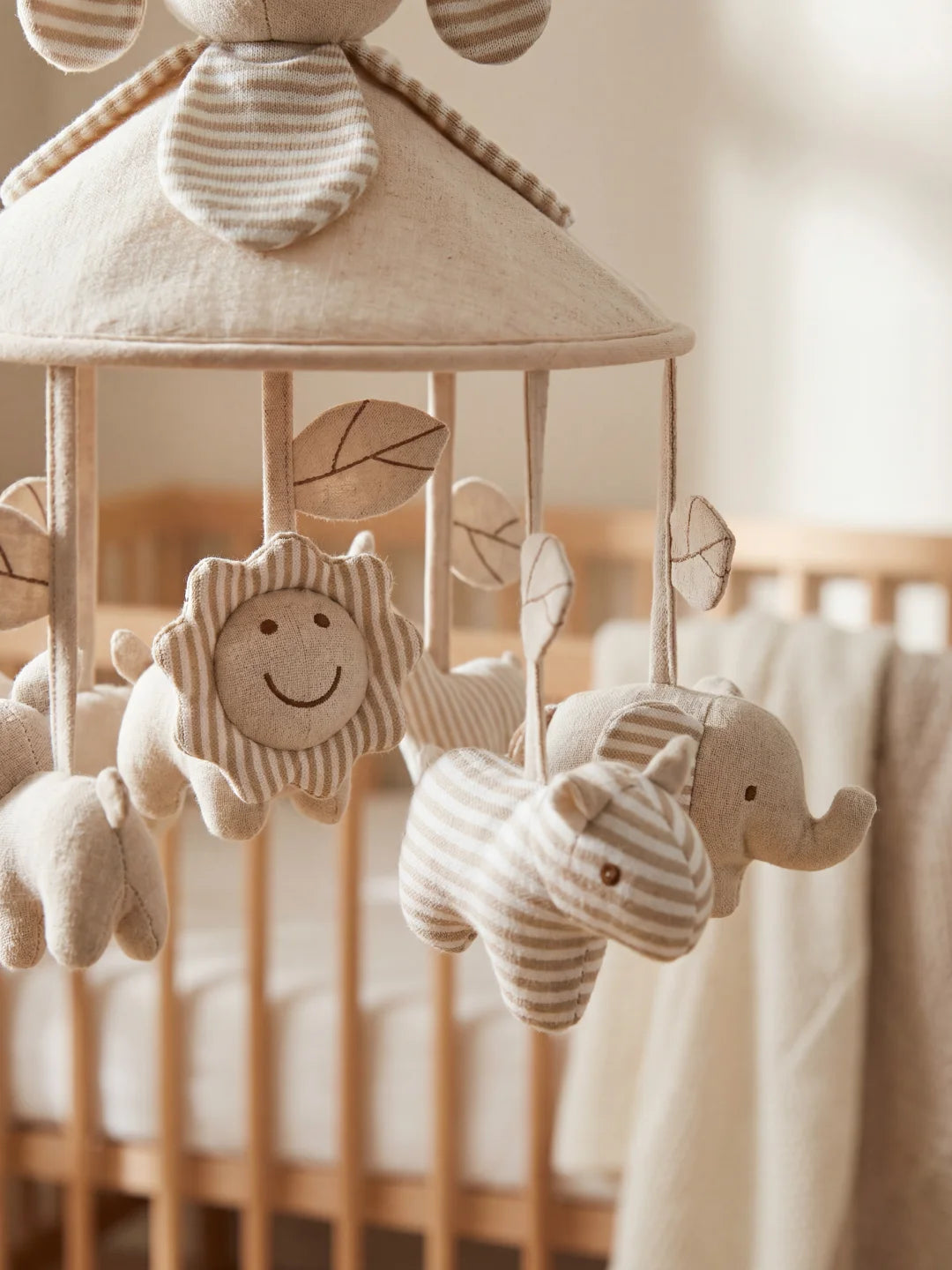 Détail des suspensions : lion souriant, éléphant et rhinocéros en tissu beige pour l'éveil de l'enfant.
