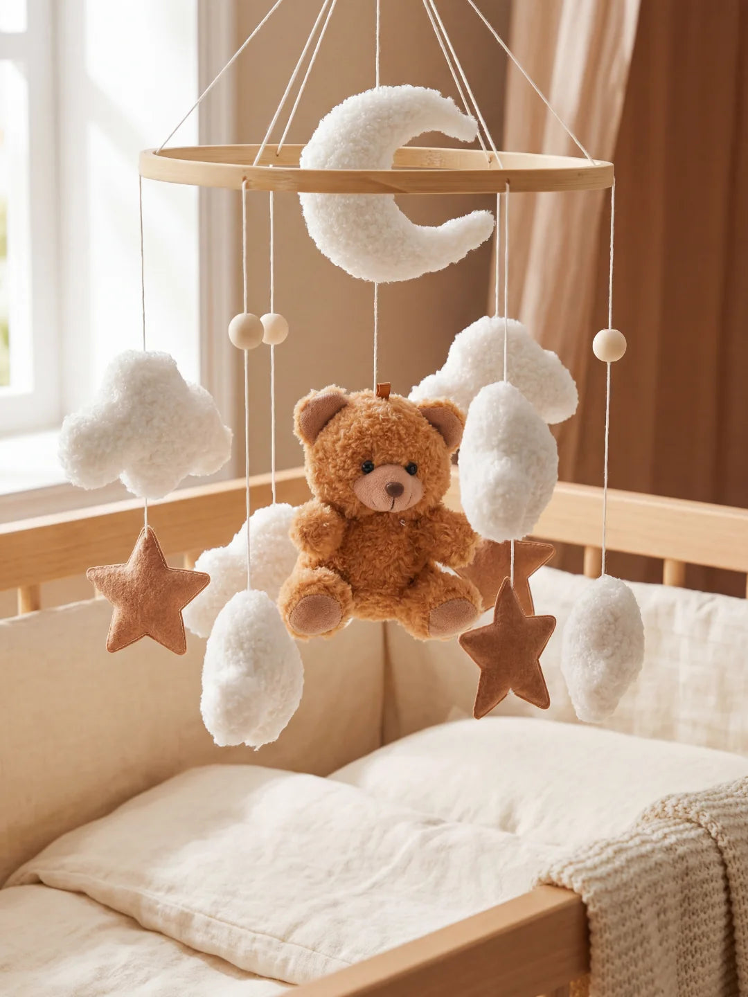 Gros plan sur l'ours en peluche central et les nuages texturés d'un mobile pour nourrisson.