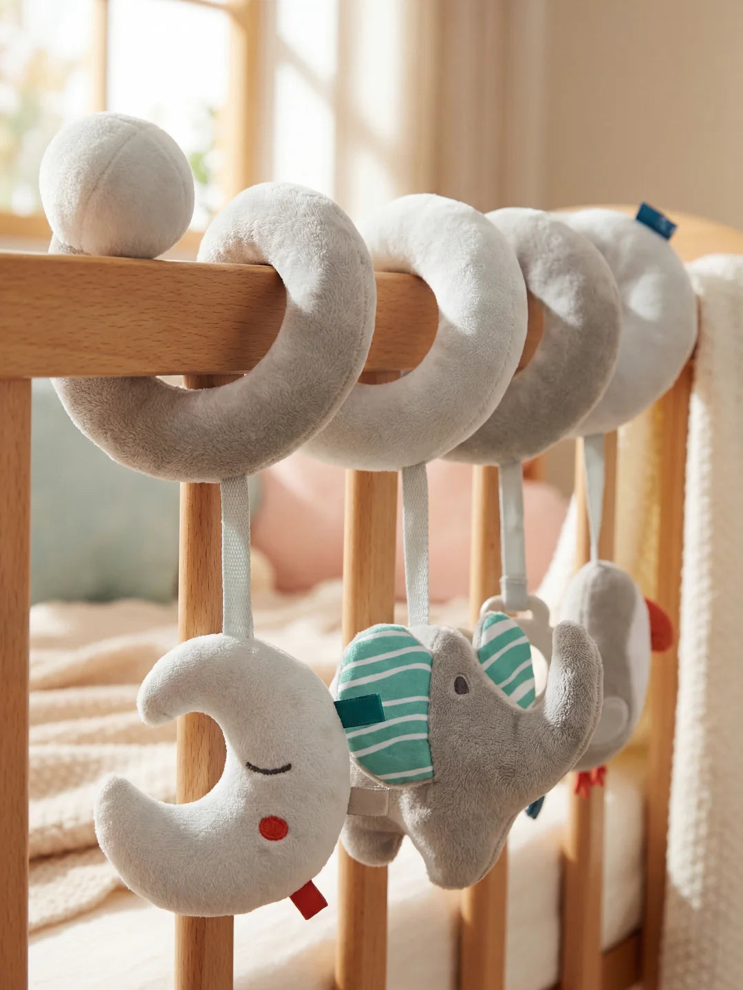 Détail des textures en velours gris de la spirale d'activité installée sur un lit de bébé.