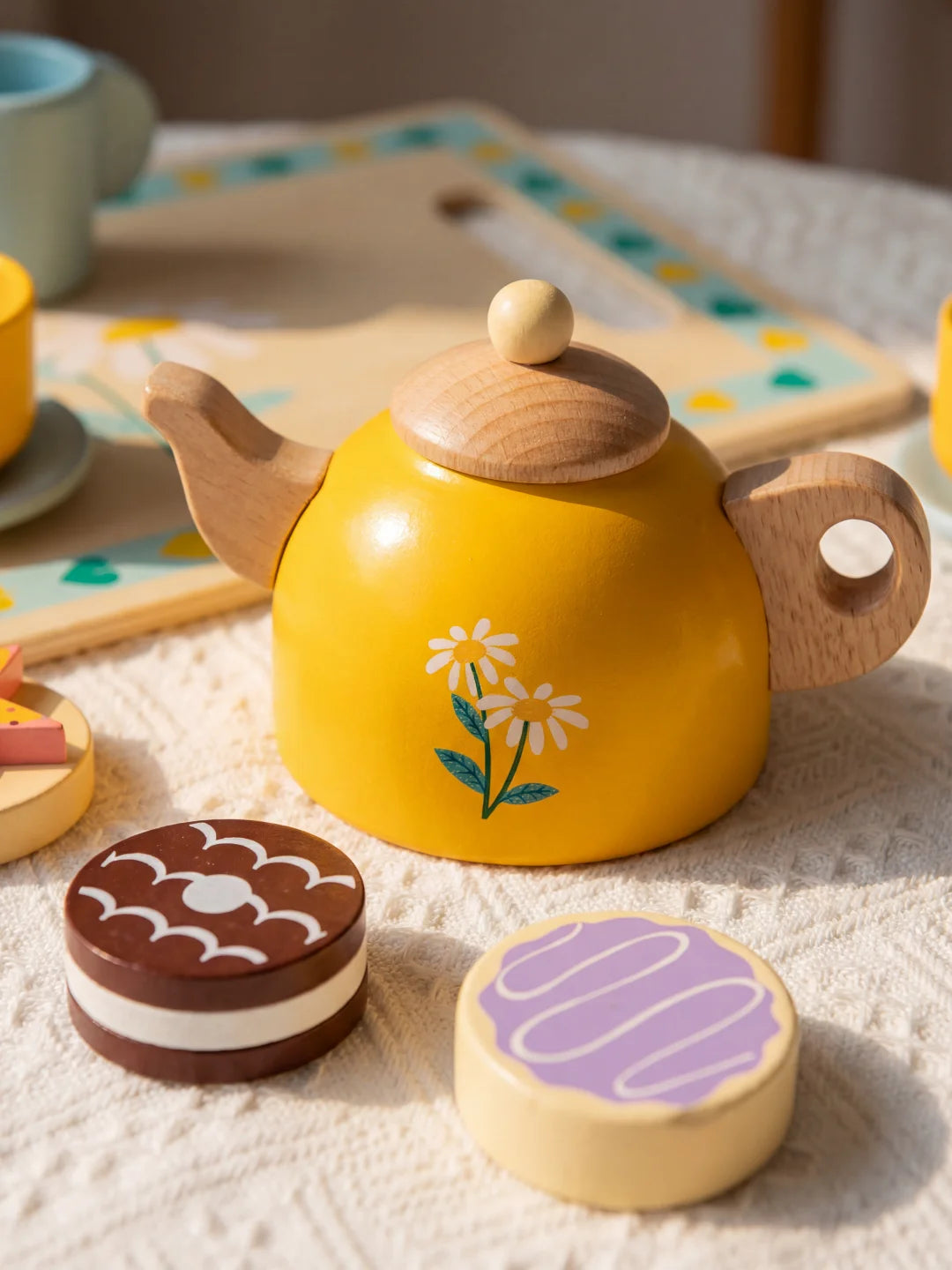 Gros plan sur des jouets d'imitation en bois incluant des gâteaux factices et une tasse jaune sur soucoupe bleue