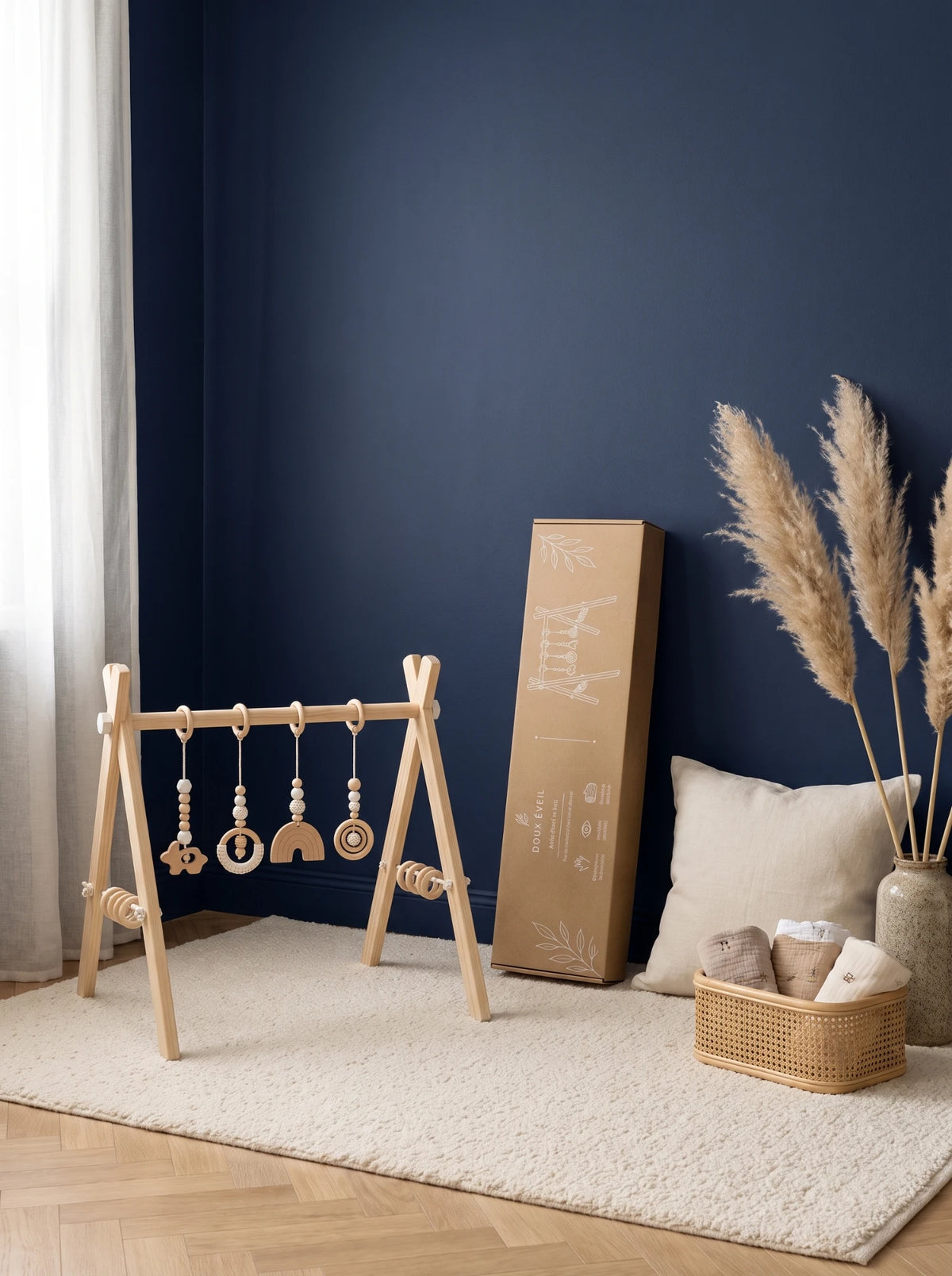 Arche d'éveil en bois blanc et sa boîte en kraft dans une chambre bébé au mur bleu marine