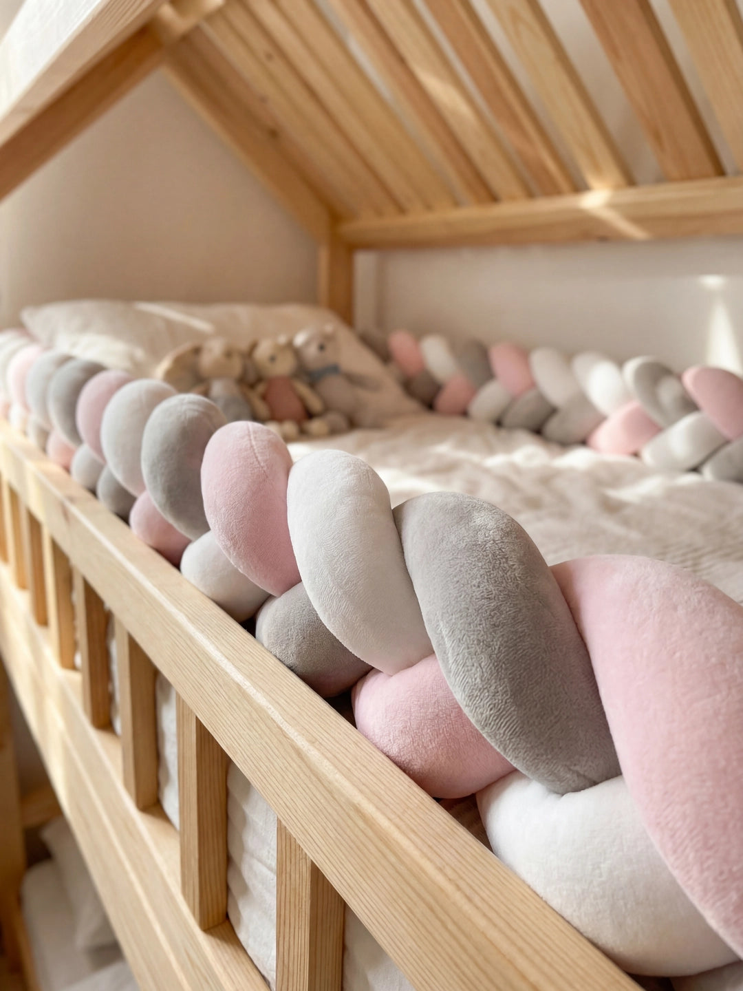 Détail de la barrière de lit en bois protégée par une tresse en velours douce pour la sécurité de l'enfant.