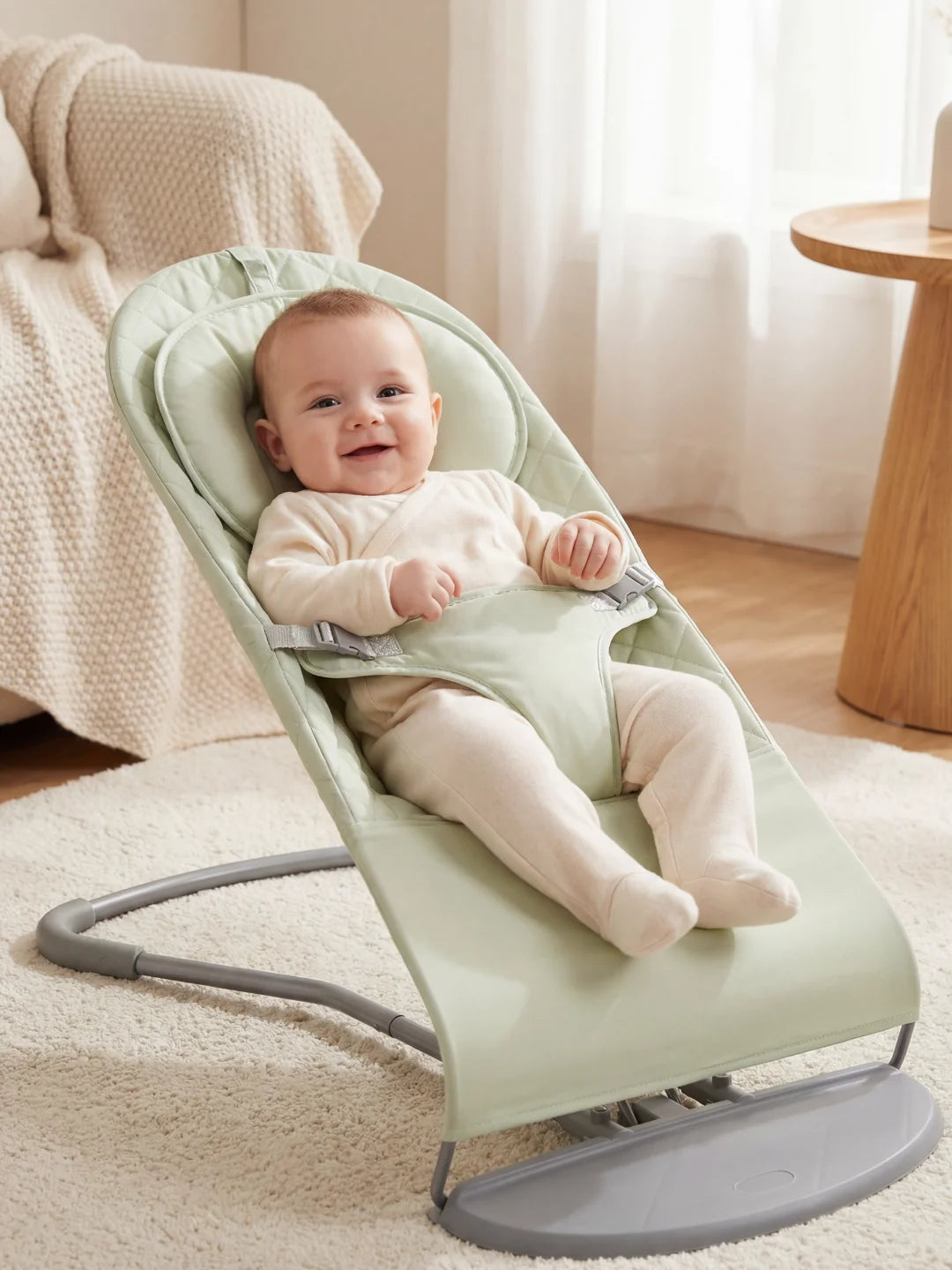 Gros plan d'un bébé heureux dans un transat molletonné couleur vert pastel avec harnais de sécurité.