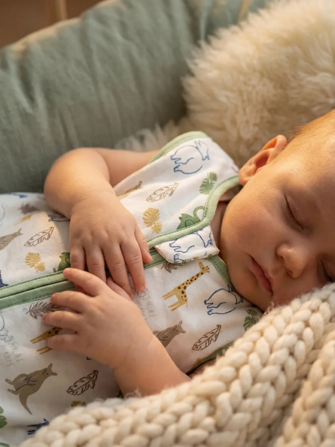 Gros plan de bébé endormi dans sa gigoteuse motif safari animaux et feuillages