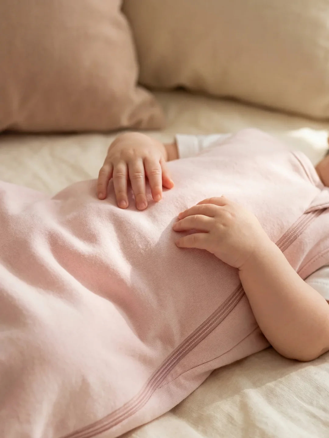 Détail des mains de bébé posées sur sa gigoteuse jersey rose pâle