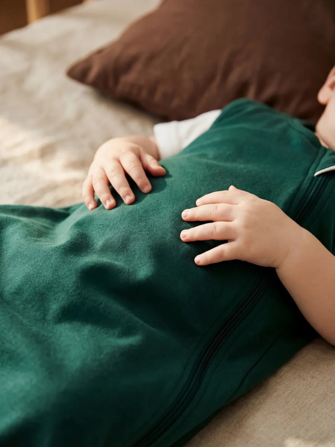 Détail des mains de bébé posées sur sa gigoteuse jersey vert sapin