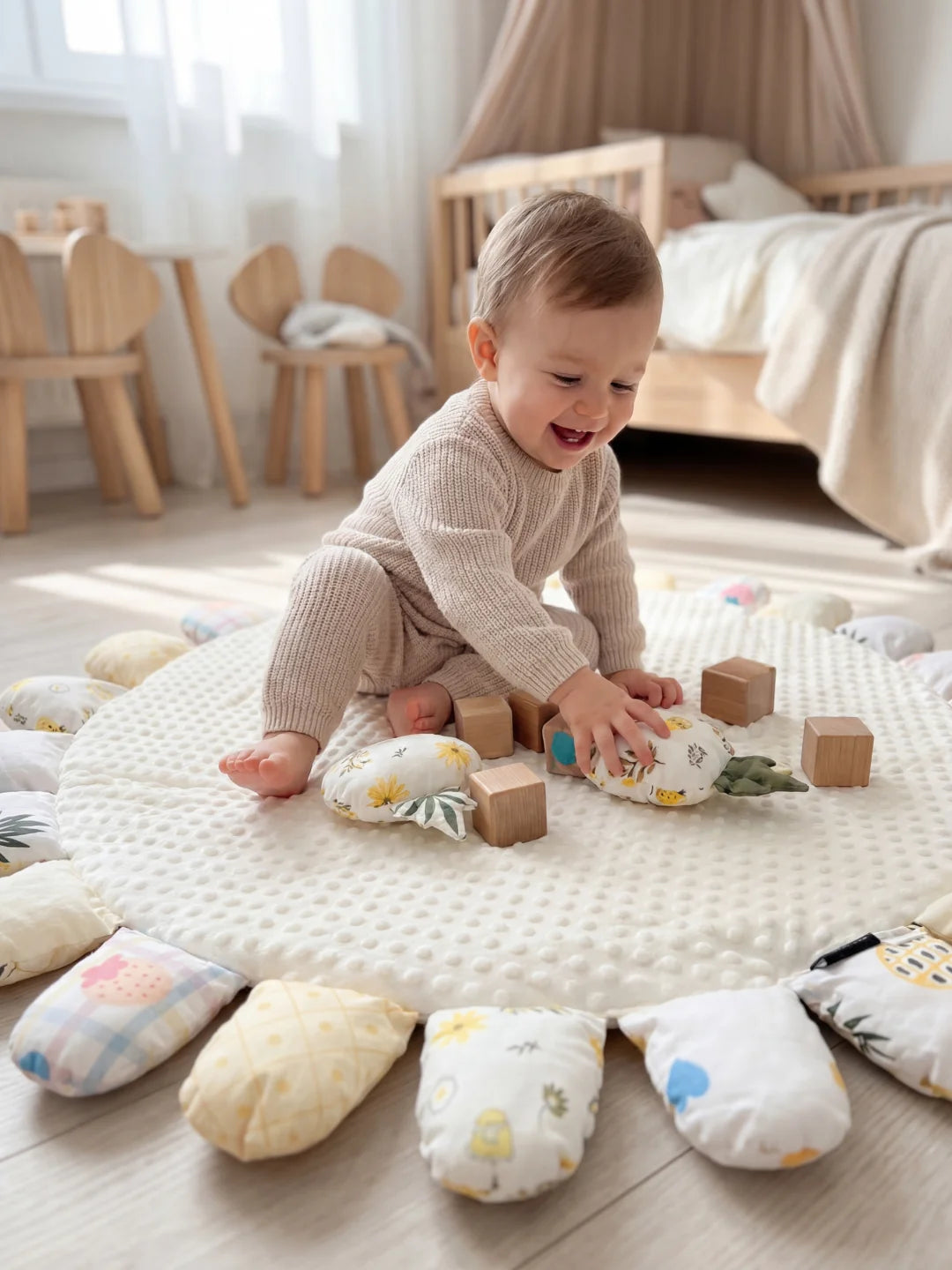 Enfant assis sur un tapis blanc manipulant les pétales rembourrés aux motifs de fruits.