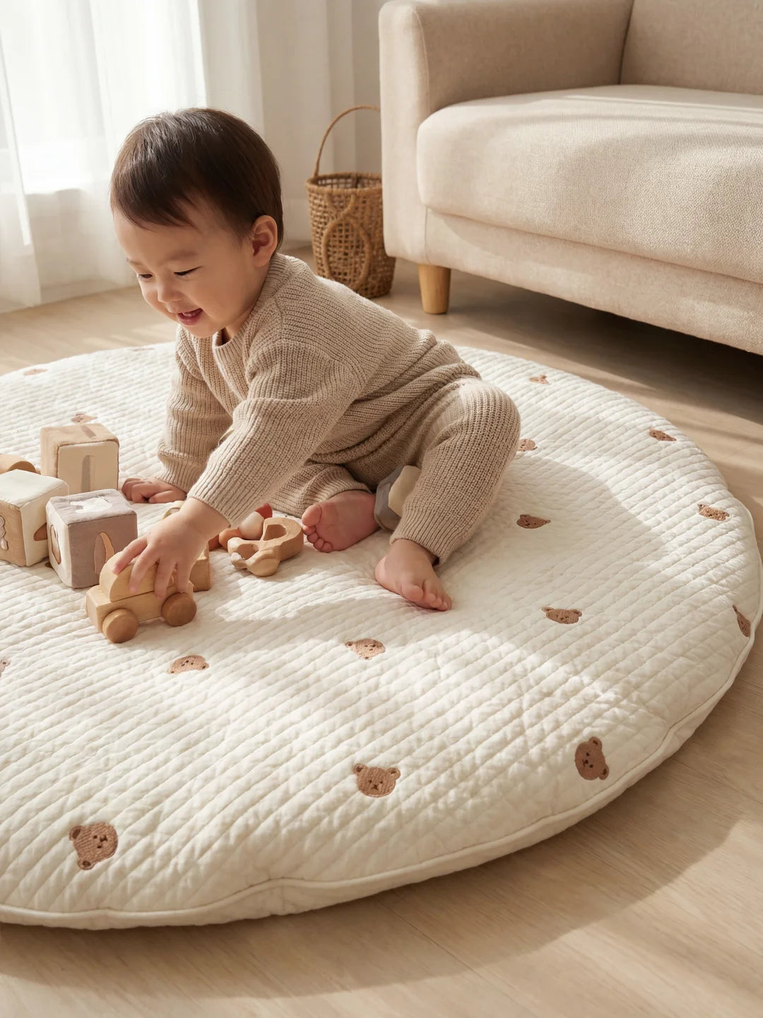 Gros plan d'un bébé s'amusant avec une petite voiture en bois sur un tapis de sol matelassé blanc aux motifs d'oursons.