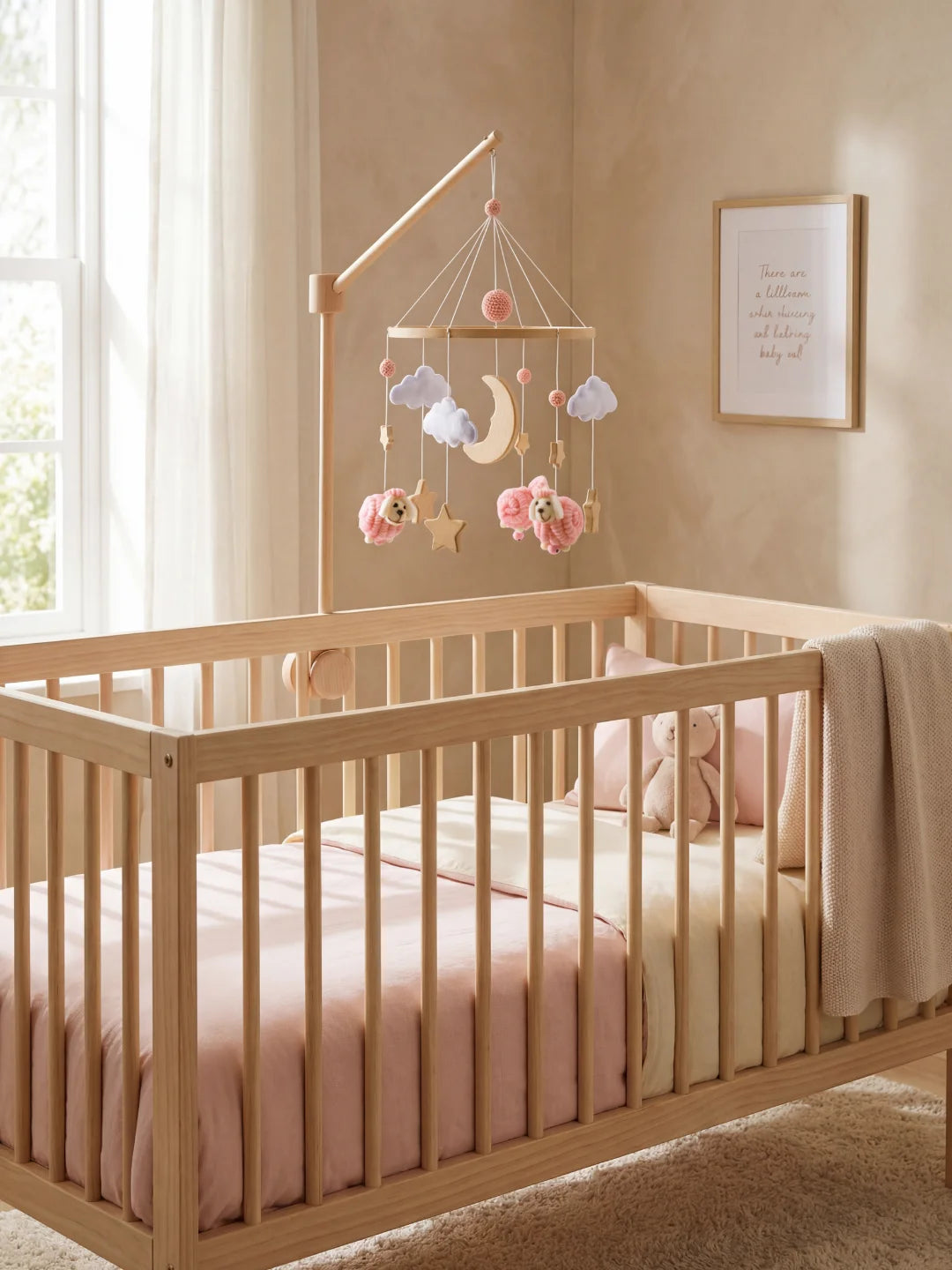 Décoration de chambre de bébé fille avec lit en bois, linge de lit rose et mobile moutons.