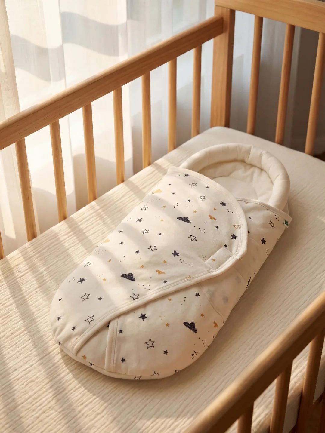 couverture d'emmaillotage bébé motif lune et étoiles posée dans un berceau