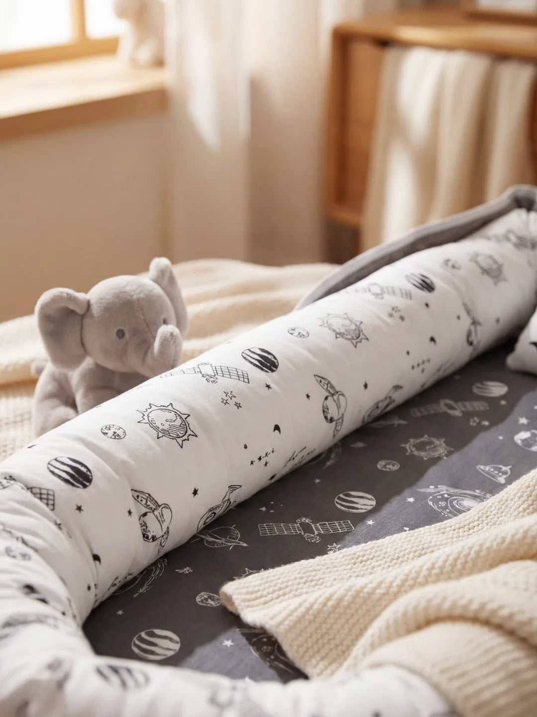 Détail du boudin rembourré du réducteur de lit bébé motif espace avec fusées et satellites