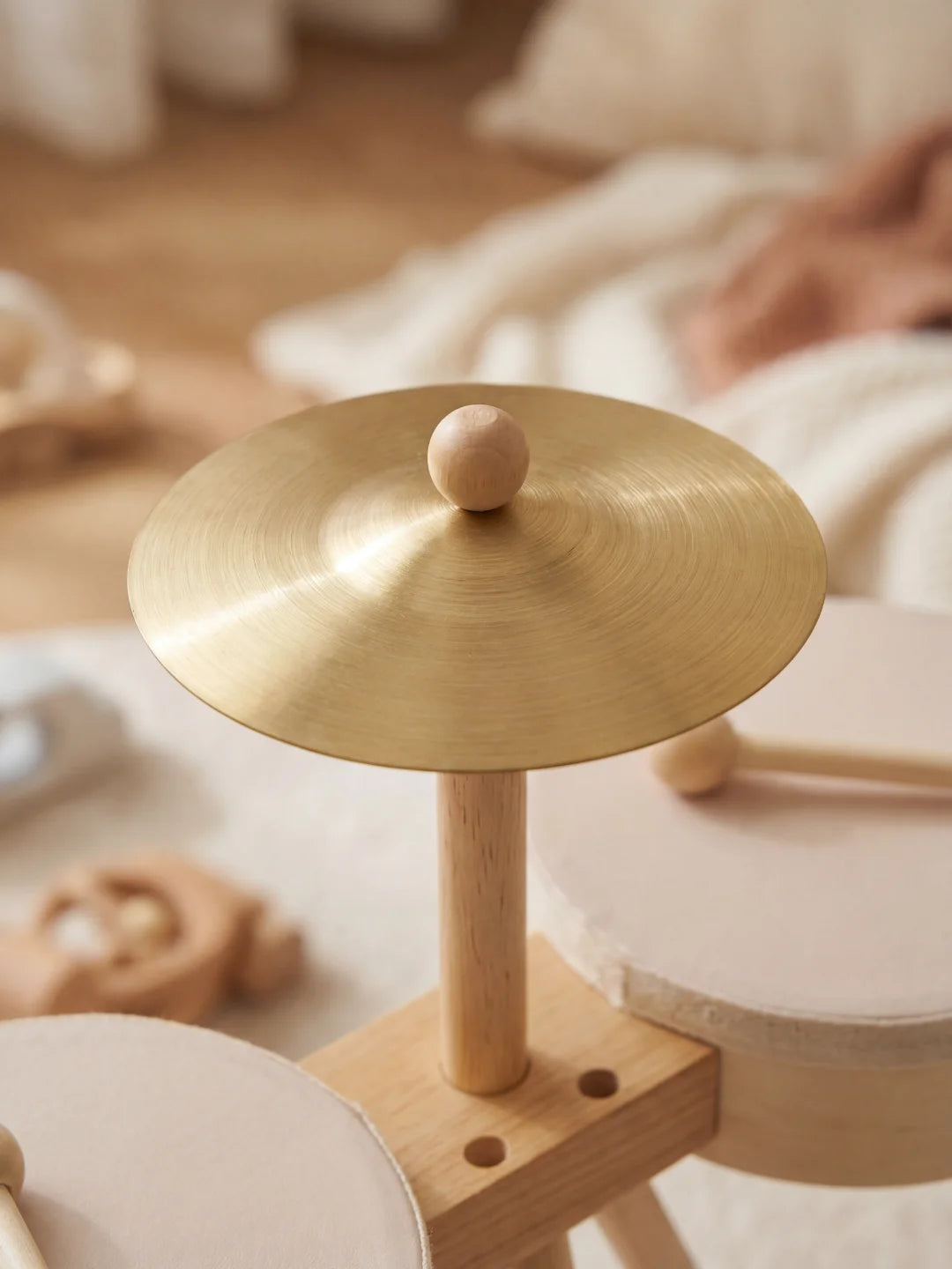 Gros plan sur la finition dorée d'une cymbale de batterie miniature et sa structure robuste en bois