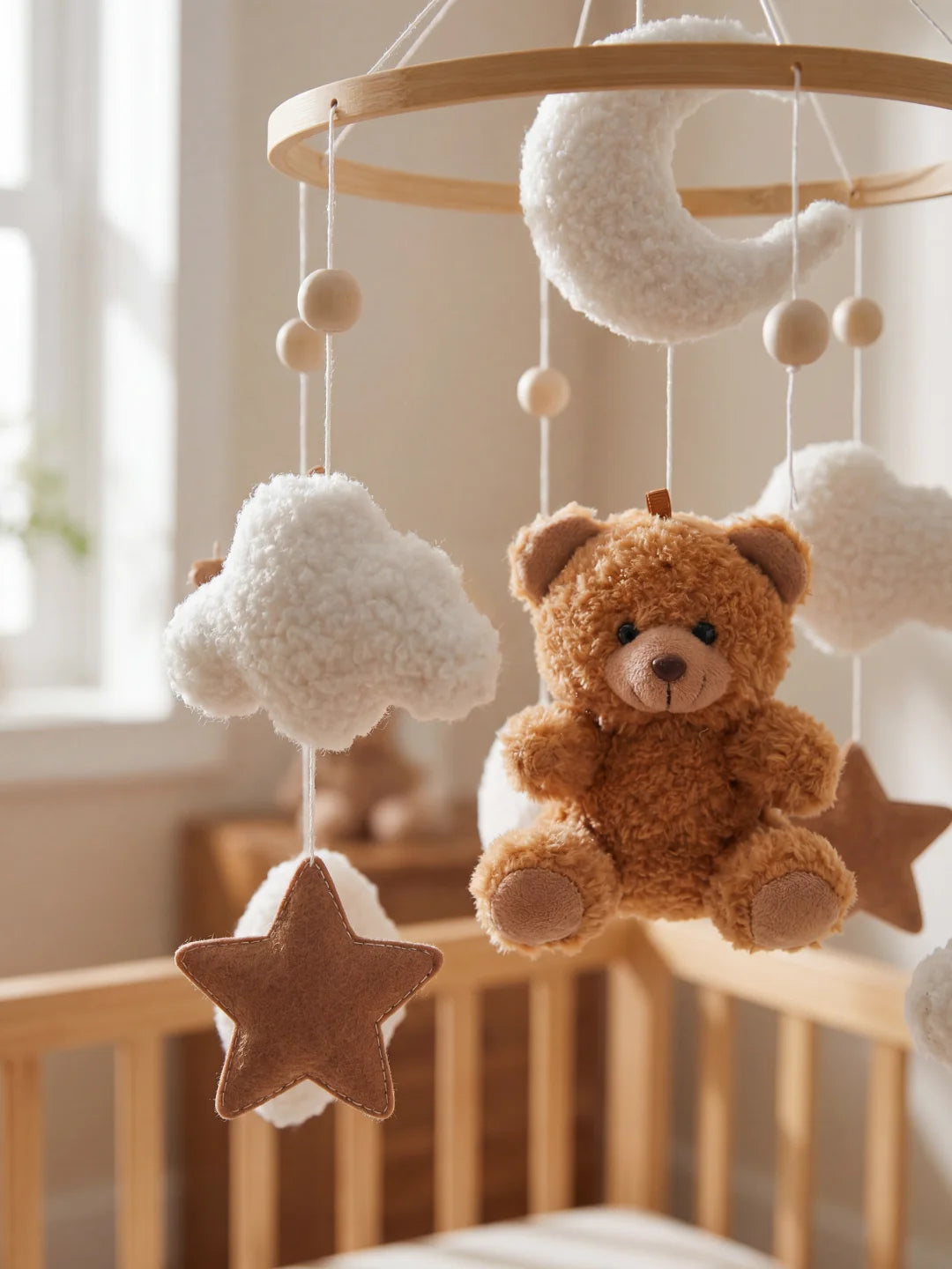 Zoom sur une étoile en feutrine marron et un ours en peluche sur un mobile bébé de qualité.