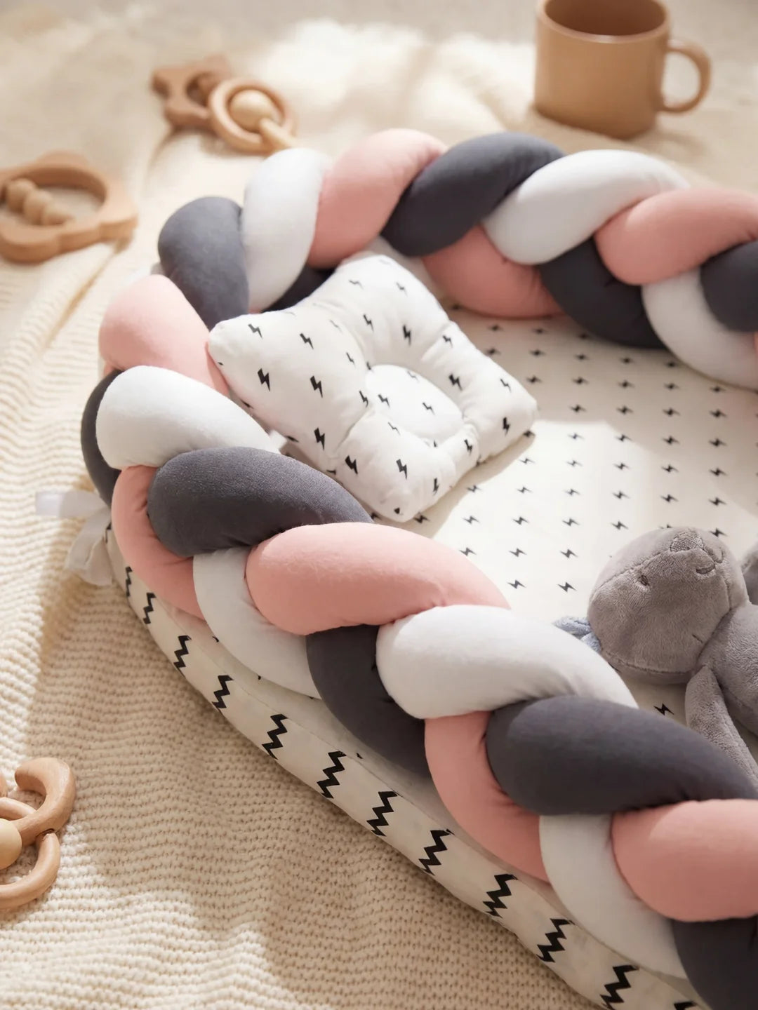 Détail du réducteur de lit tressé rose anthracite et blanc avec coussin et peluche