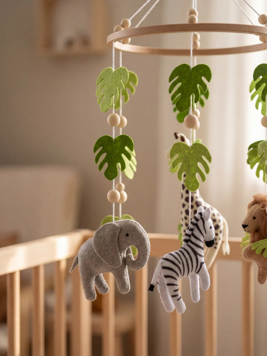 Zoom sur l'éléphant gris et le zèbre suspendus à un mobile d'éveil style safari.