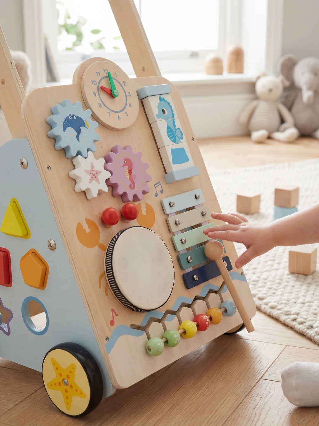 Main d'enfant jouant avec le tambour et le xylophone du chariot de marche Le P'tit Marin.