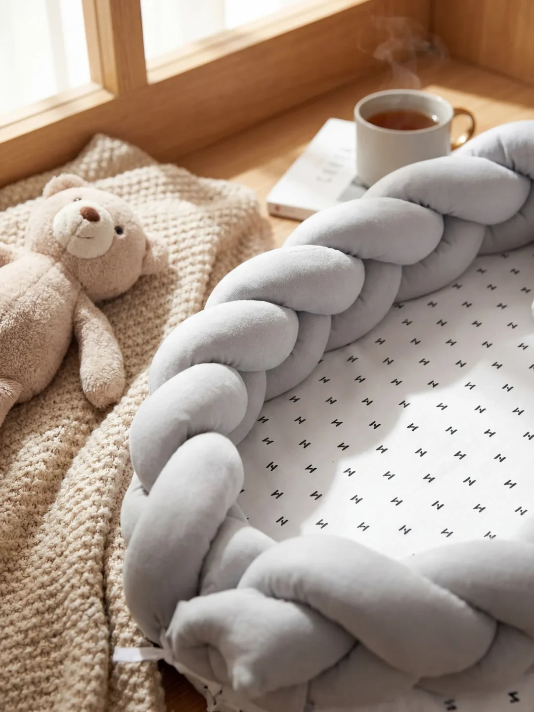 Détail de la tresse velours gris d'un réducteur de lit bébé avec peluche