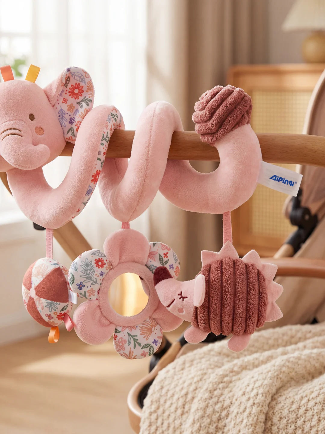 Zoom sur les hochets de la spirale éléphant : miroir fleur, hérisson en velours et balle texturée.