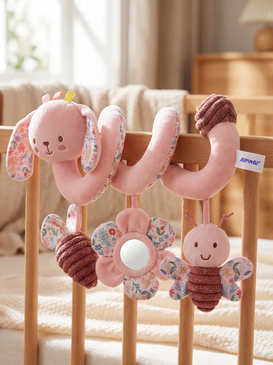 Gros plan sur les suspensions de la spirale lapin : hochet papillon, miroir et abeille texturée.