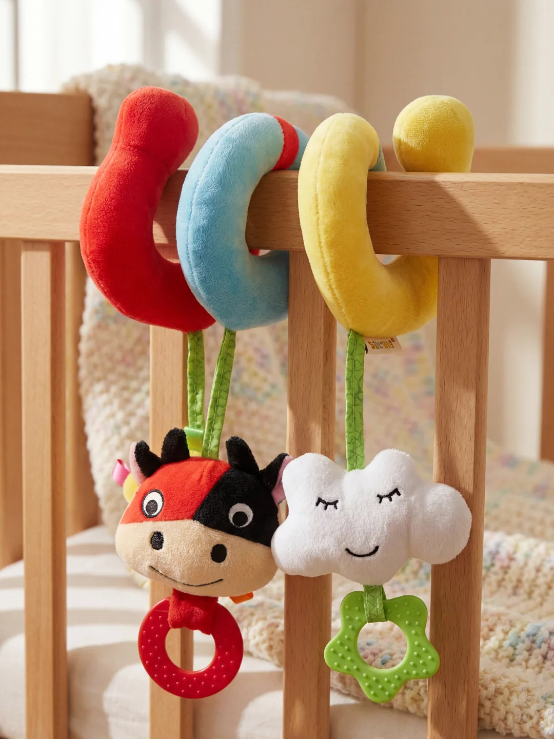 Gros plan sur la vachette en peluche et le nuage suspendu avec anneaux de dentition texturés.