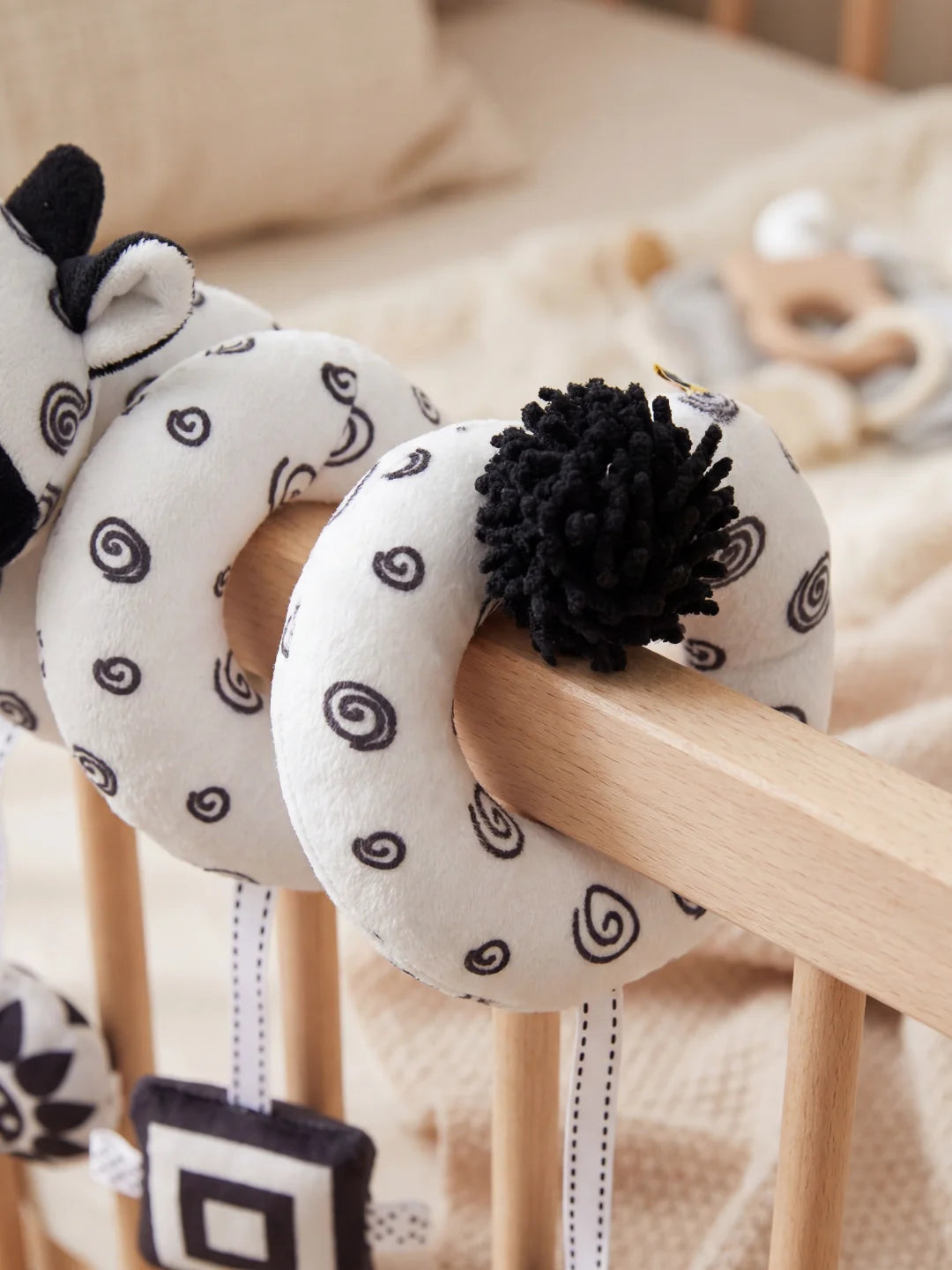 Gros plan sur le pompon noir texturé et les motifs à spirales du jouet d'éveil pour nouveau-né.