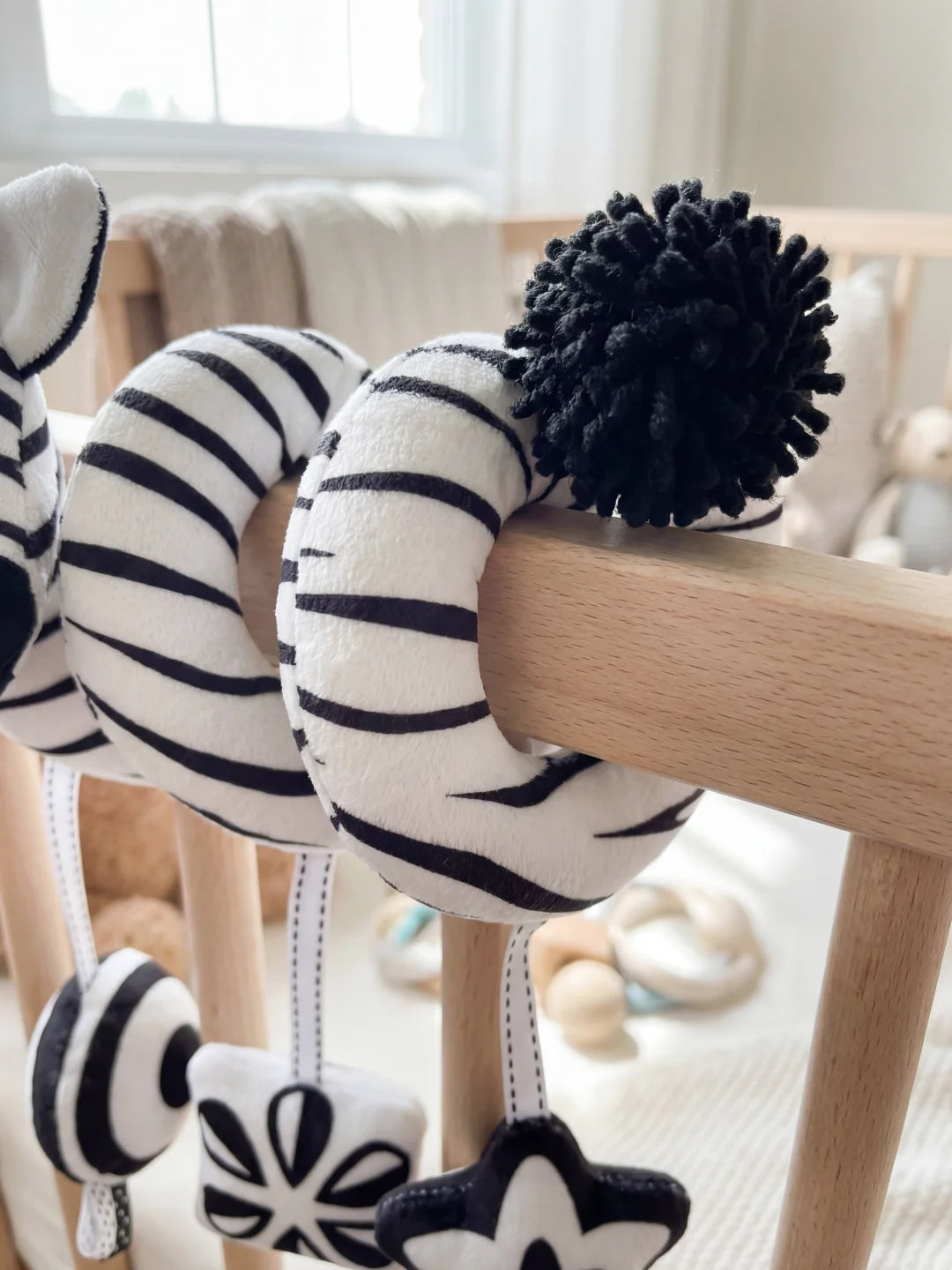 Gros plan sur le pompon noir et les rayures du jouet zèbre pour la stimulation tactile de bébé.