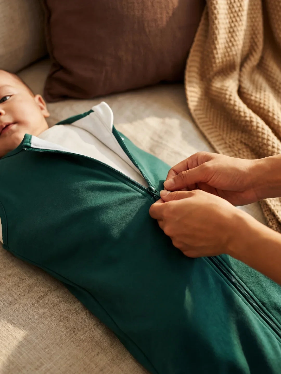 Parent ouvrant la fermeture éclair de la gigoteuse jersey vert sapin sur bébé