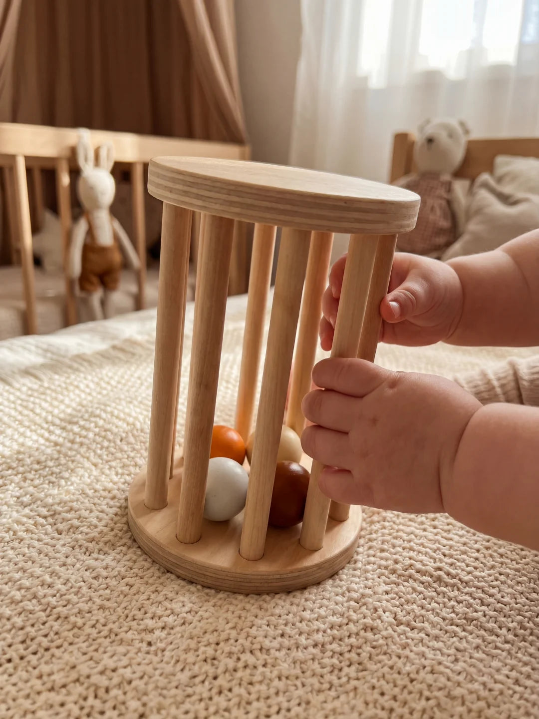 Mains d'un bébé manipulant un hochet cage en bois contenant des perles colorées.