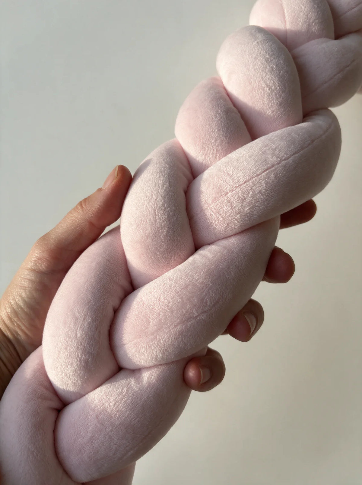 Tresse de lit velours rose tenue en main montrant le tressage 3 brins, Évinel