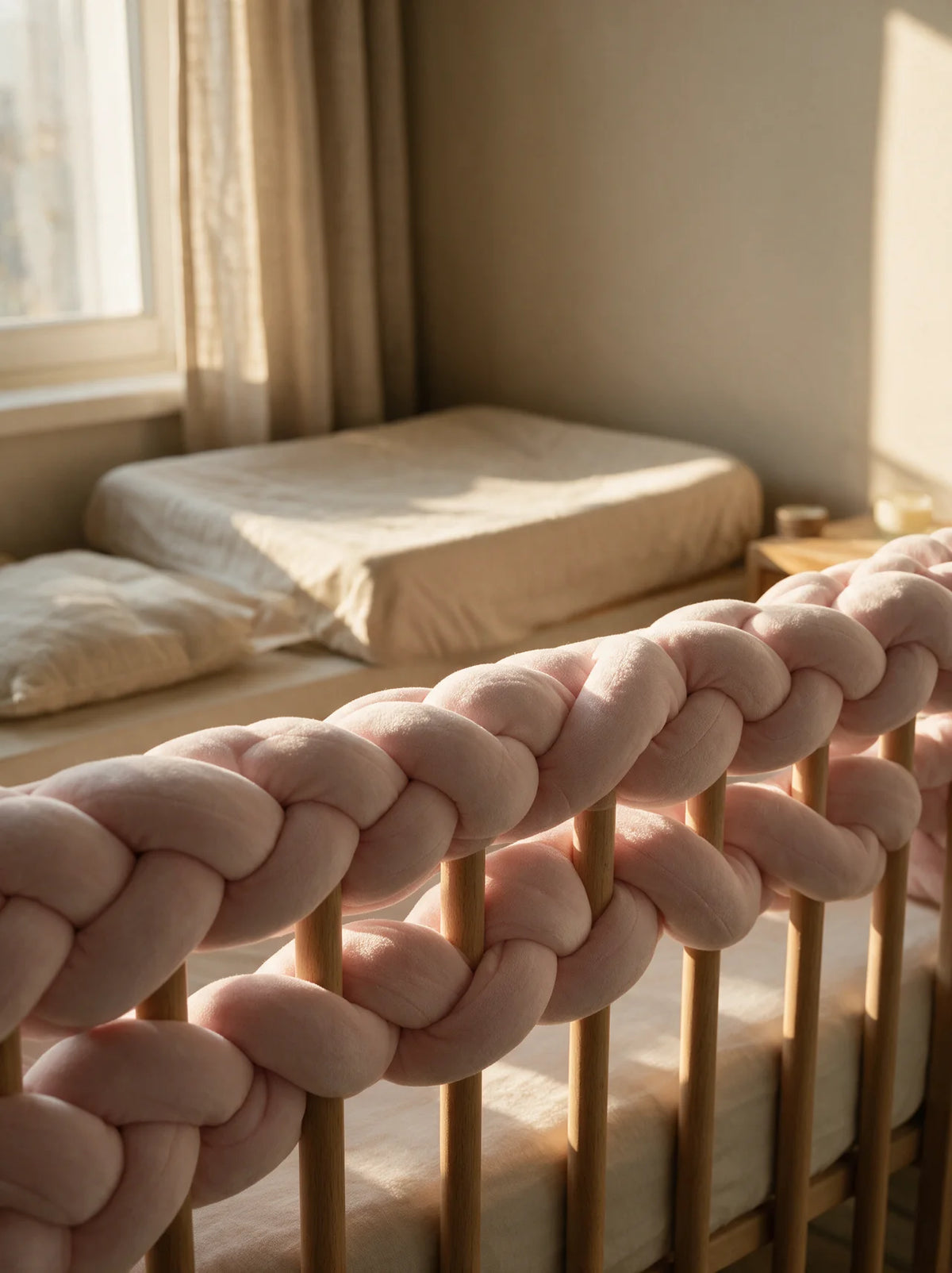 Tresse de lit 3 brins rose installée en tour de lit sur un lit à barreaux bébé