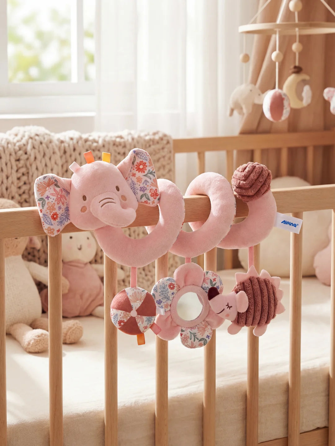 Spirale d'activité éléphant rose fixée sur un lit à barreaux dans une chambre d'enfant.