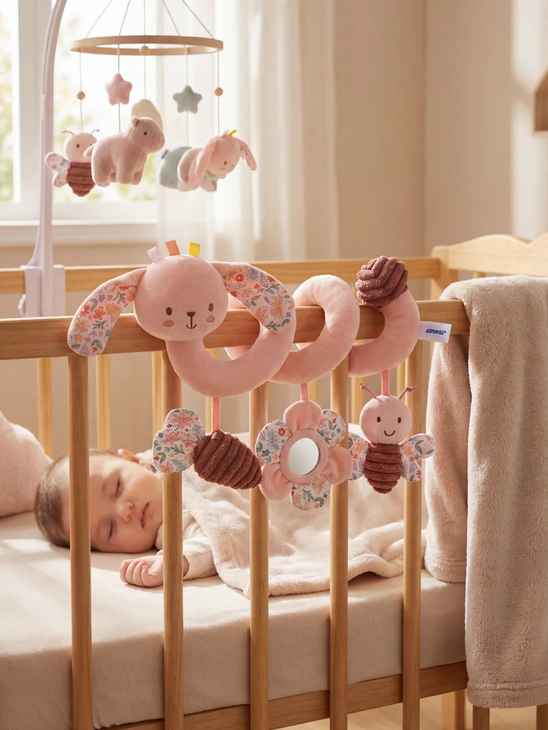 Bébé endormi sous une spirale d'activité lapin rose avec hochet papillon et miroir fleur.