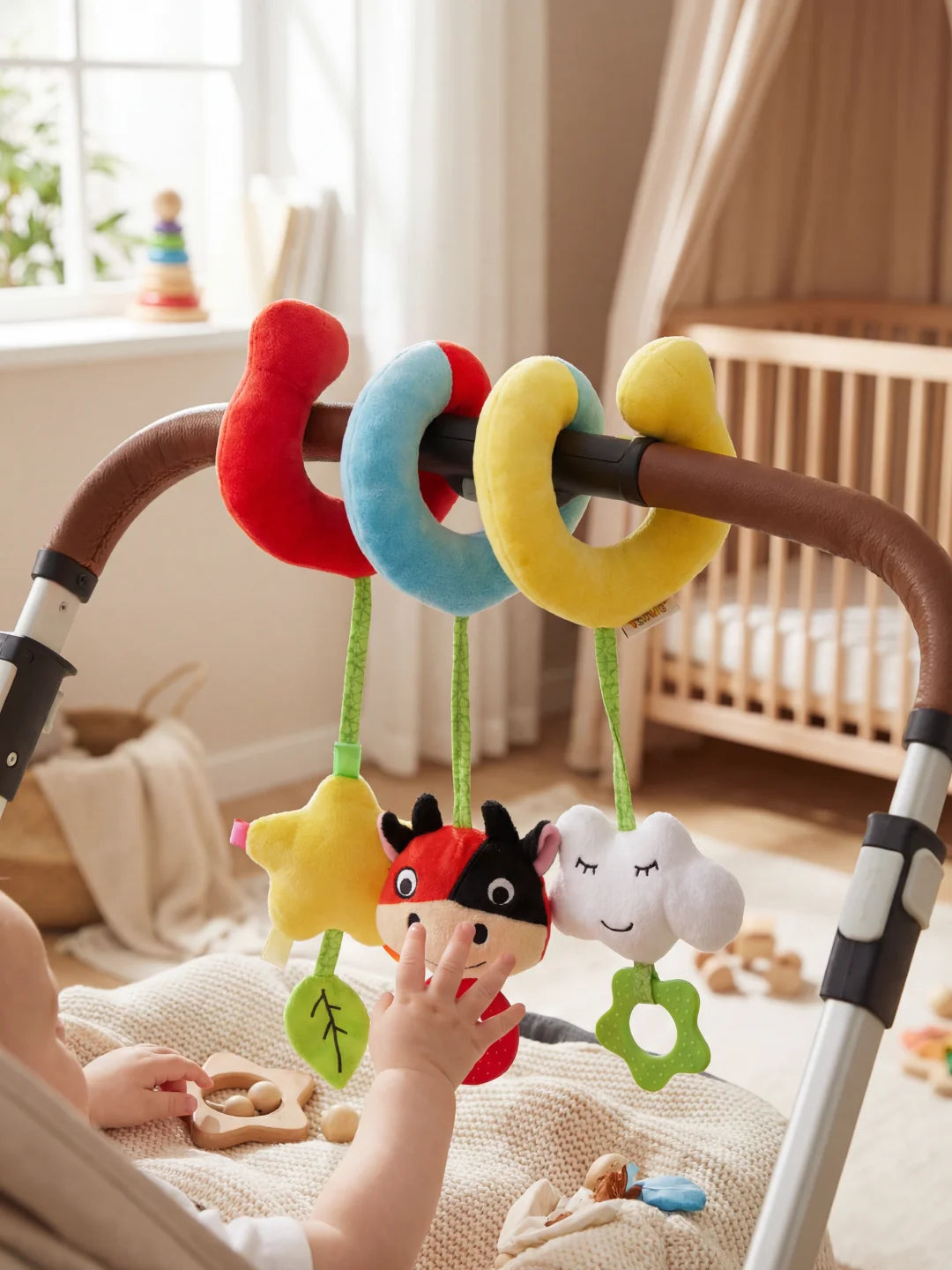 Spirale d'activité vache avec anneau de dentition rouge et étoile jaune installée sur une poussette.