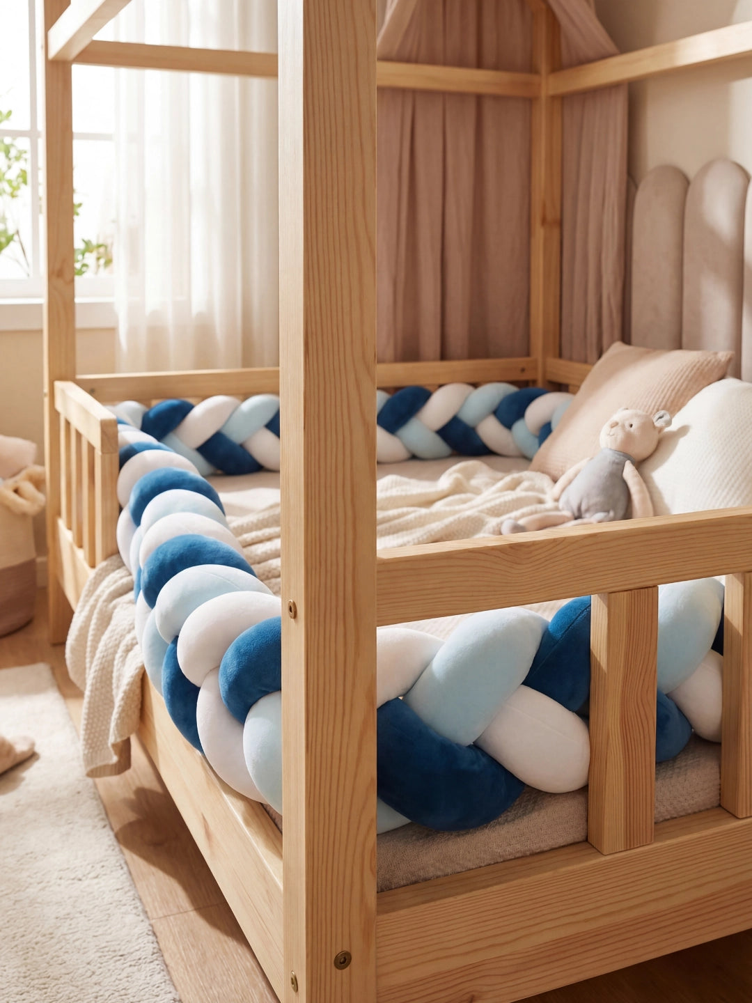 Lit cabane en bois massif équipé d'un tour de lit tressé bleu marine, ciel et blanc pour la sécurité de l'enfant.