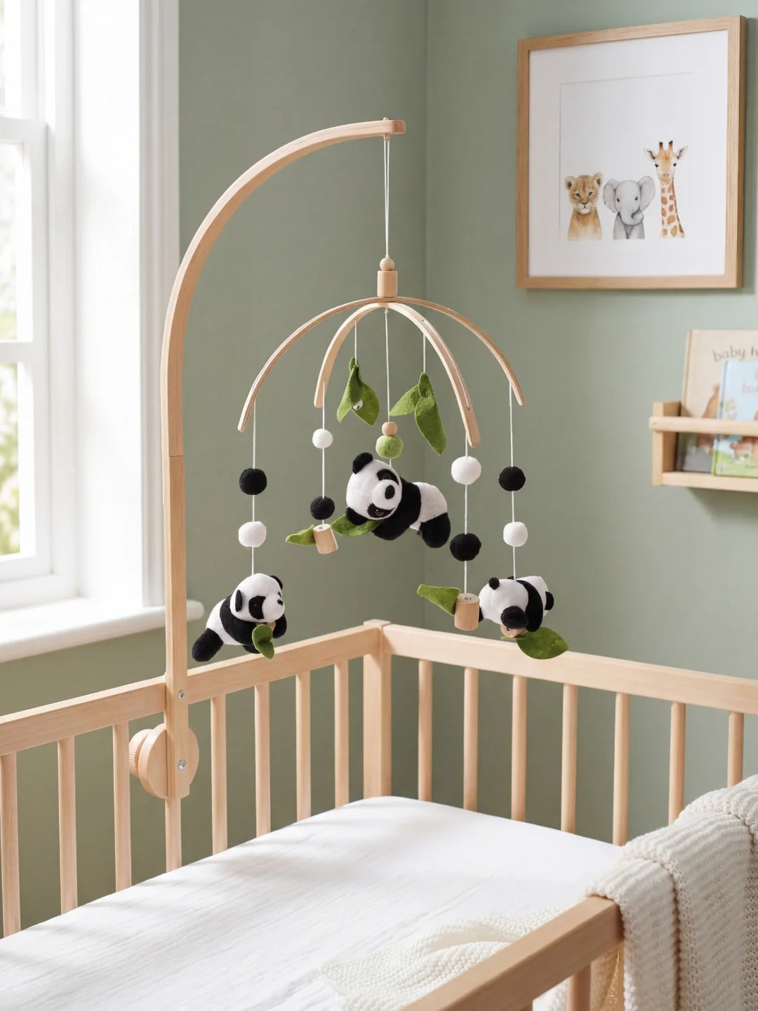 Mobile bébé avec pandas en peluche, feuilles de bambou vertes et boules de laine noires et blanches.