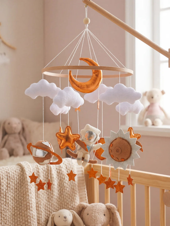 Mobile d'éveil galaxie avec finitions cuivrées et argentées installé dans une chambre d'enfant moderne.