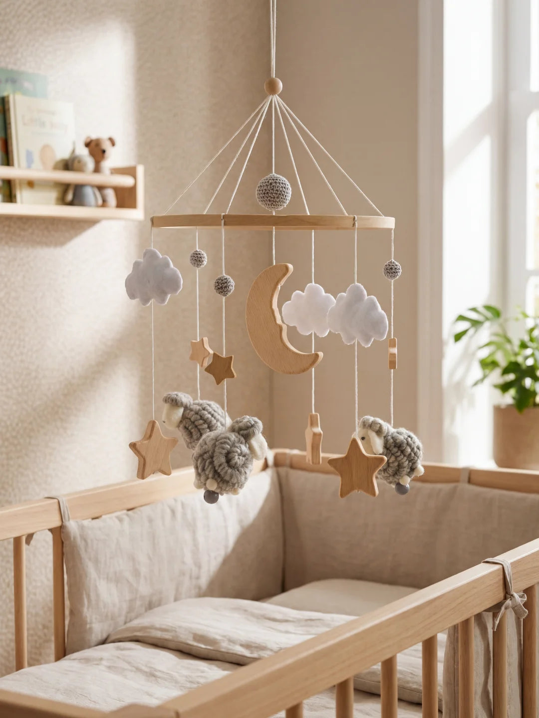 Mobile d'éveil pour nouveau-né avec moutons gris, nuages blancs et lune en bois au-dessus du lit.