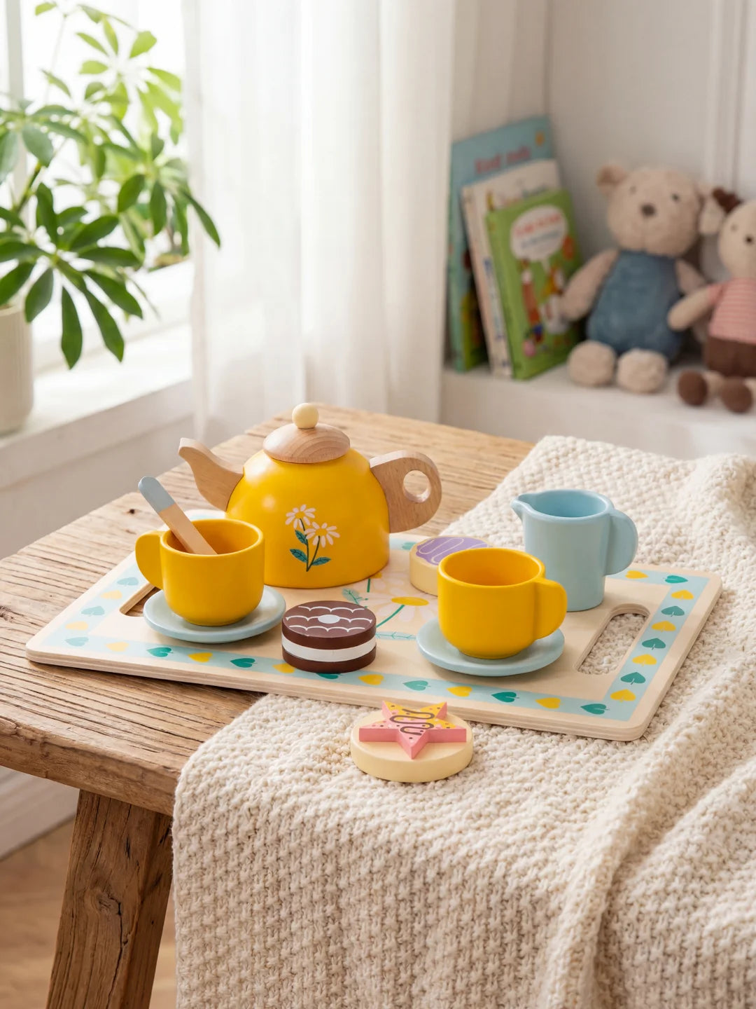 Vue d'ensemble d'un plateau de jeu en bois avec théière, tasses bleues et biscuits décoratifs.