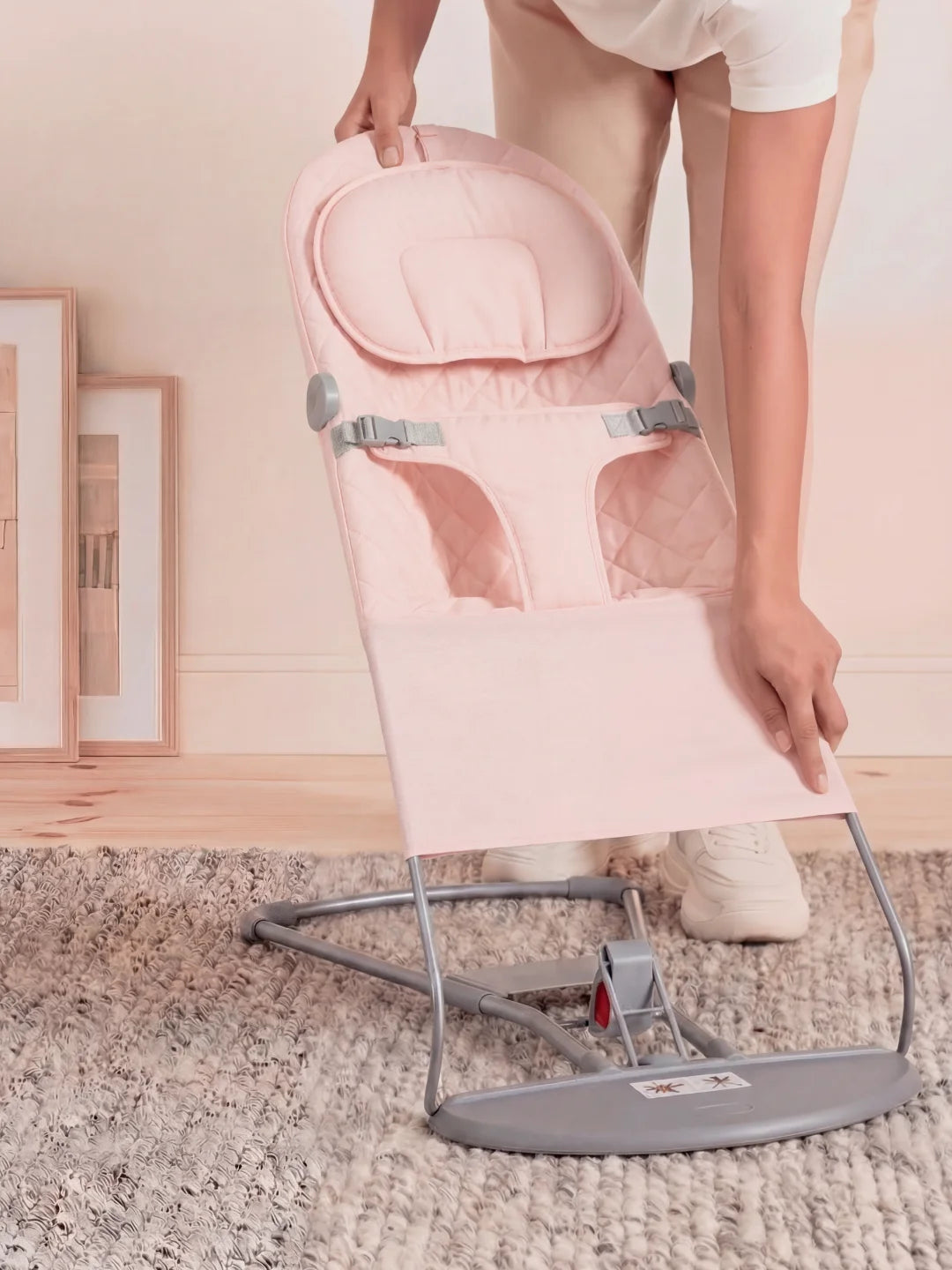 Démonstration de la manipulation et de la légèreté du transat bébé rose par un adulte.