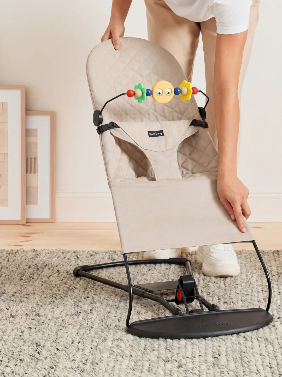 Démonstration de la légèreté et de la facilité de transport du transat beige plié par un parent.