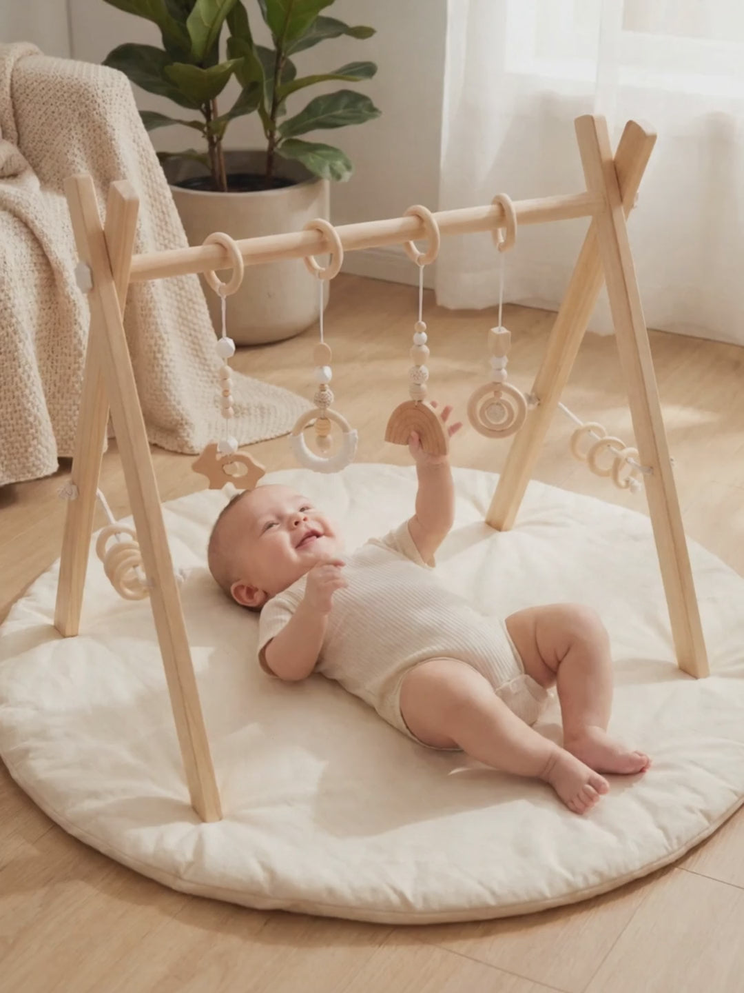 Bébé allongé sous l'arche d'éveil en bois qui attrape l'arc-en-ciel en bois et sourit